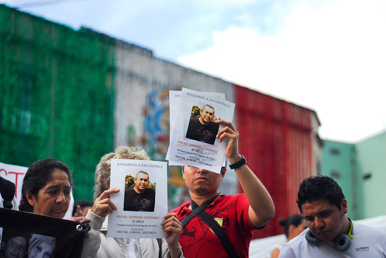 Personas sosteniendo carteles de personas desaparecidas