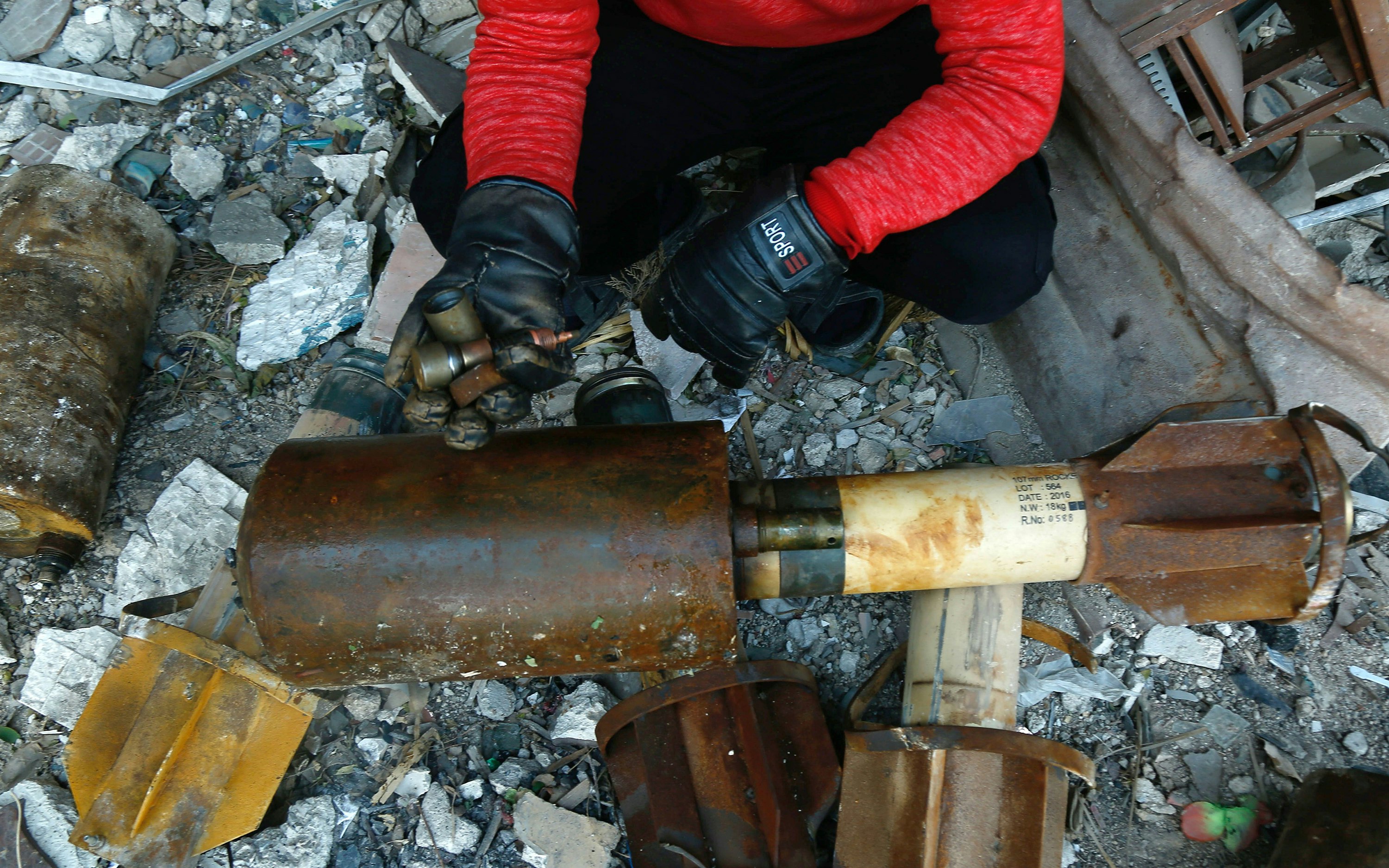 A person next to debris and bomb parts