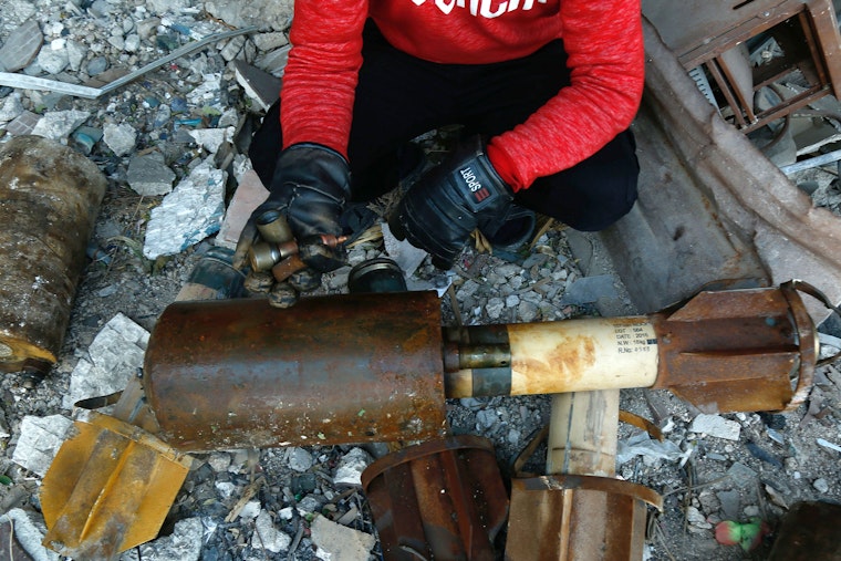 A person next to debris and bomb parts