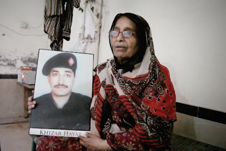 Still image “Bring It Back: Khizar Hayat’s Story of Death Row in Pakistan.” International law bans executing prisoners who are suffering from mental illnesses. But in Pakistan, Khizar Hayat, a person with schizophrenia, has been sentenced to death. A woman holding a framed picture
