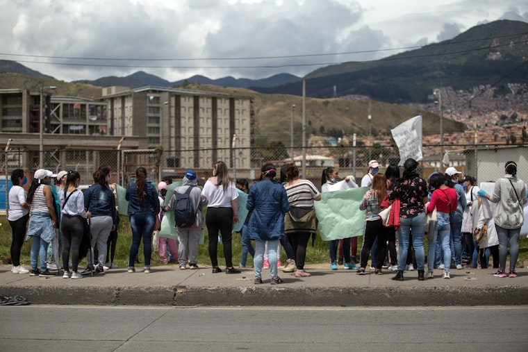 A group of people stand at a fence outside of a prison complex