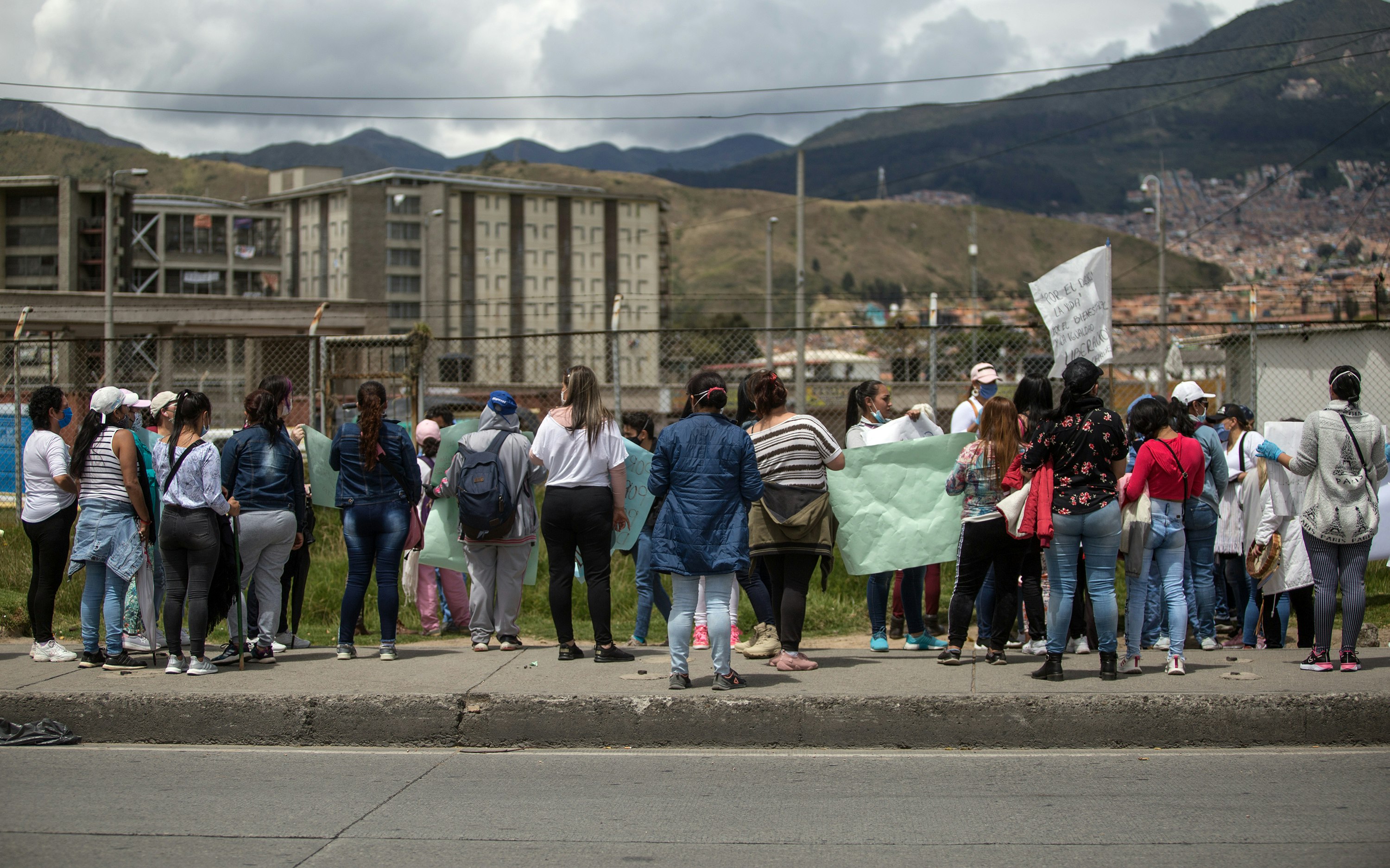 A group of people stand at a fence outside of a prison complex