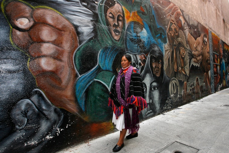 A woman walking in front of a colorful mural