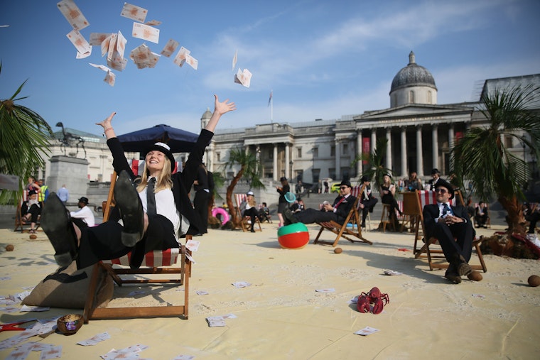 Demonstrators in fancy costume tossing play money in the air