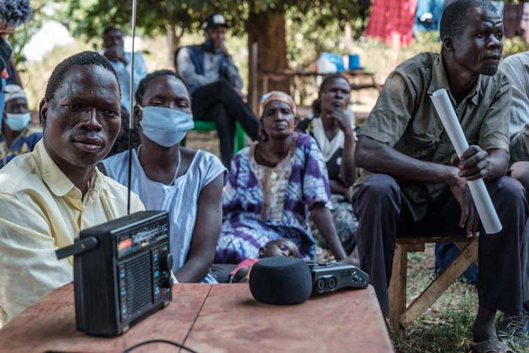 A community listens to the ICC verdict broadcasted in Lukodi, Uganda