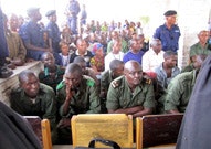 Lt. Col. Kibibi Mutware sitting at the front of a large group at trial