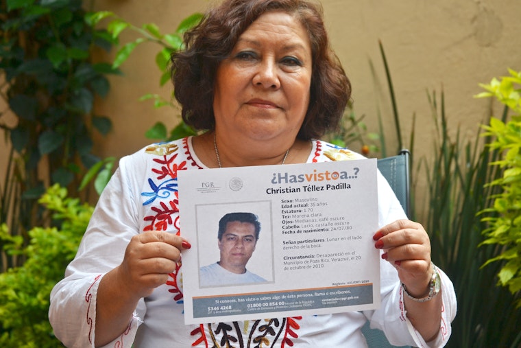 Mother holding sign of disappeared son