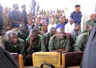 Men in military uniform sitting in front row of crowd at their trial.