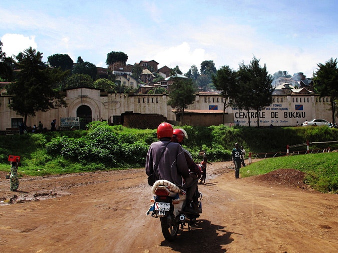 Two men on a motorcycle in front of Bukavu Central Prison