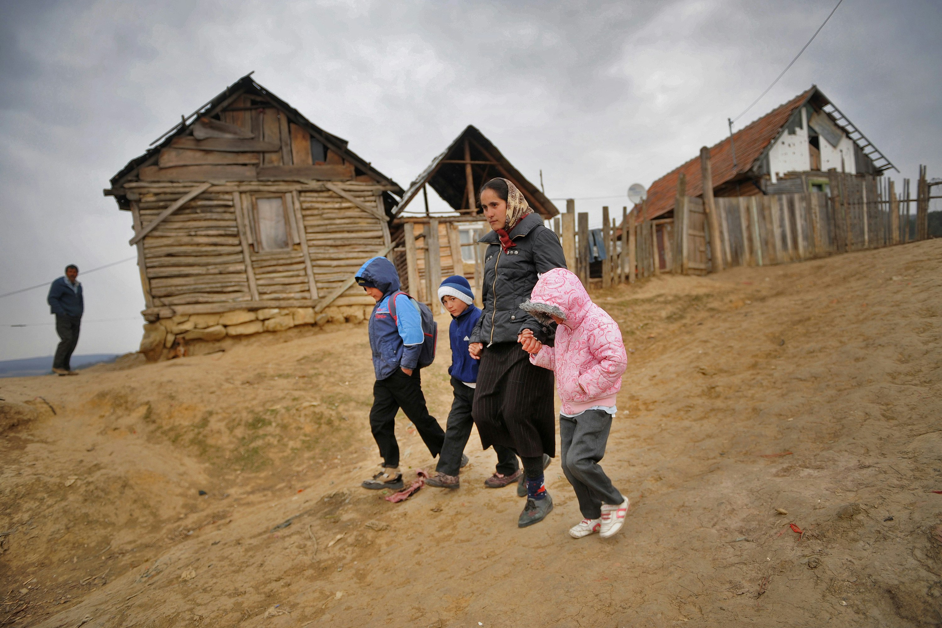A woman and three children walking on an unpaved road