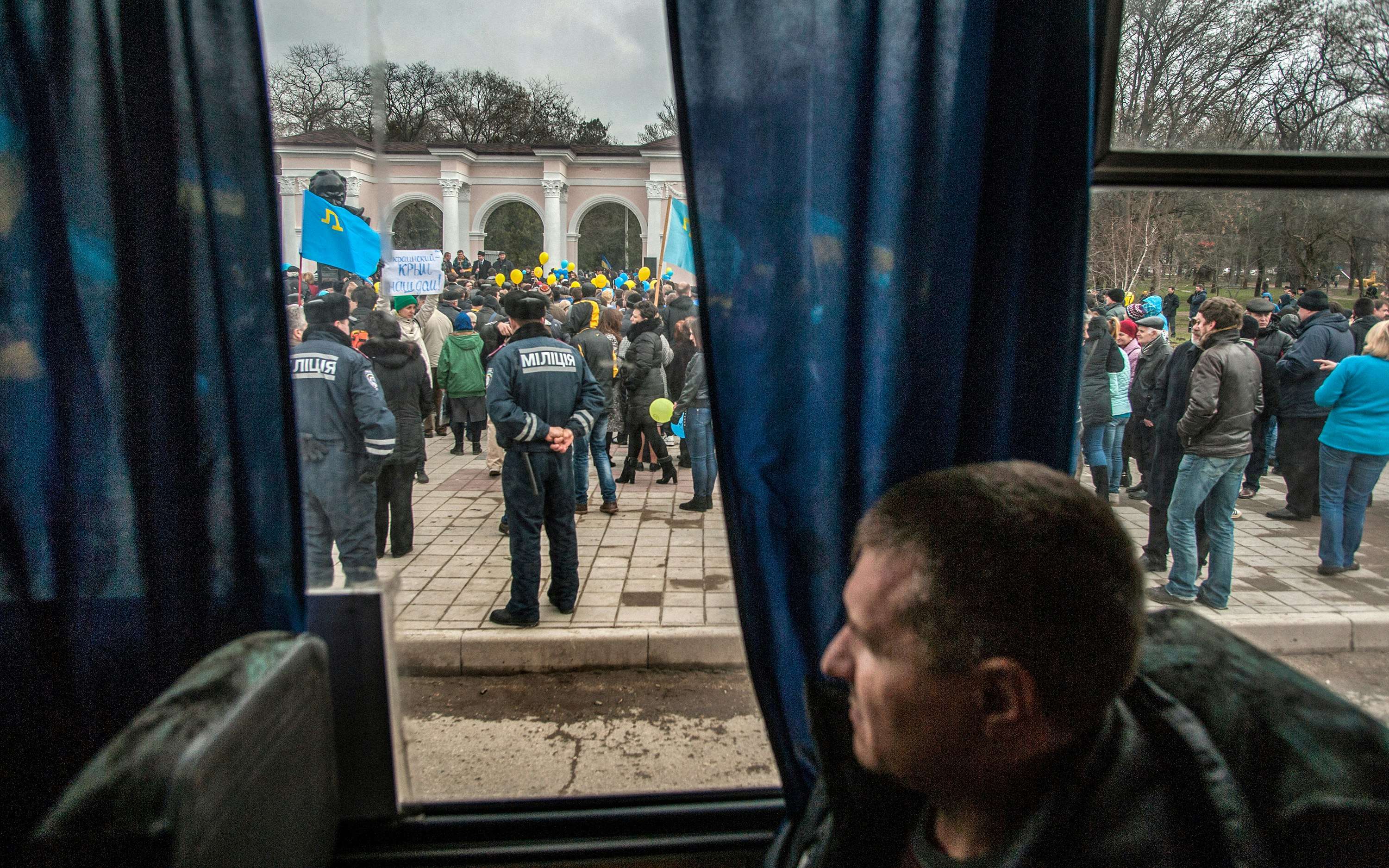 A man views a crowd of protesters from inside a bus