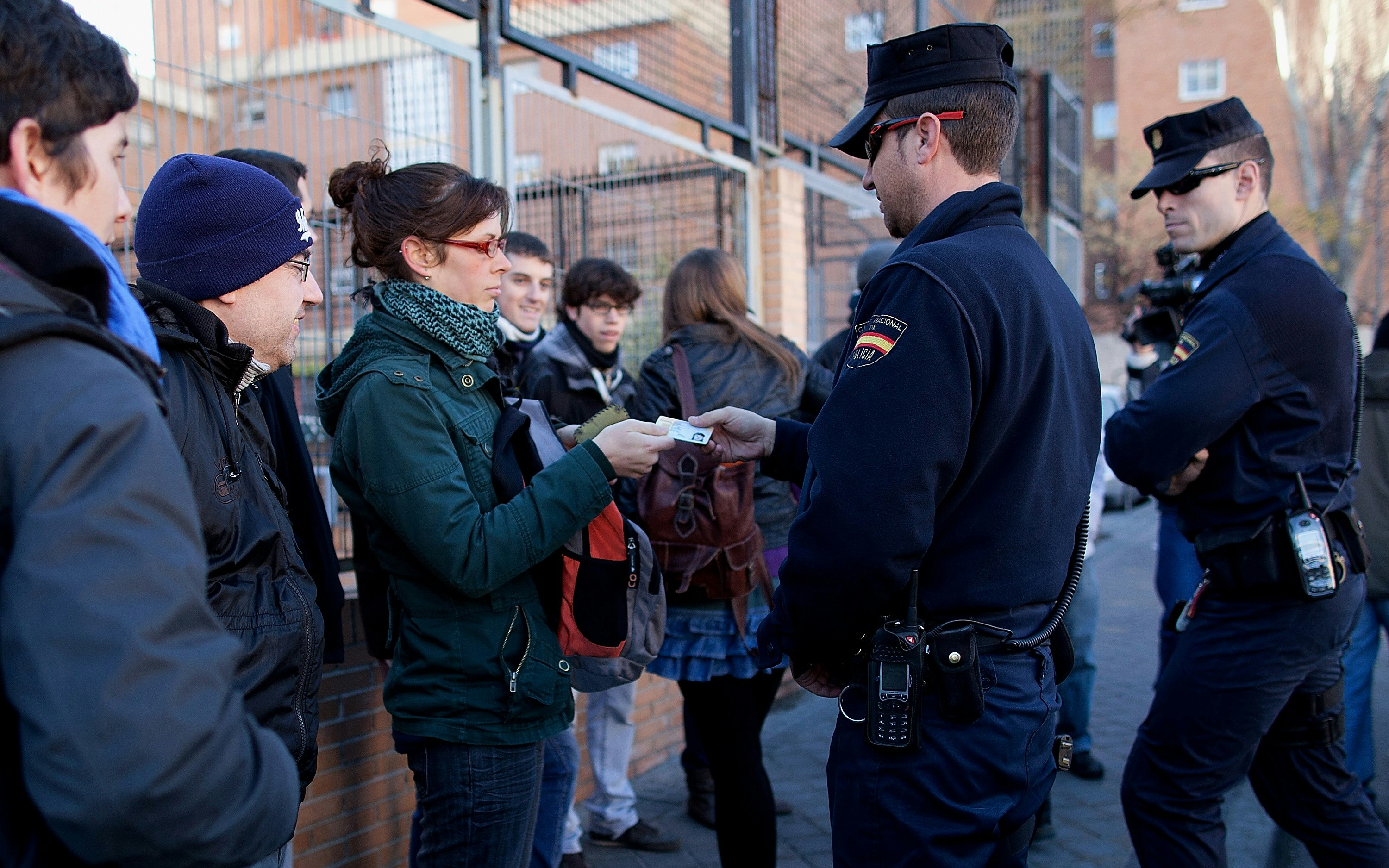 A woman in a group handing her identification card to a police officer